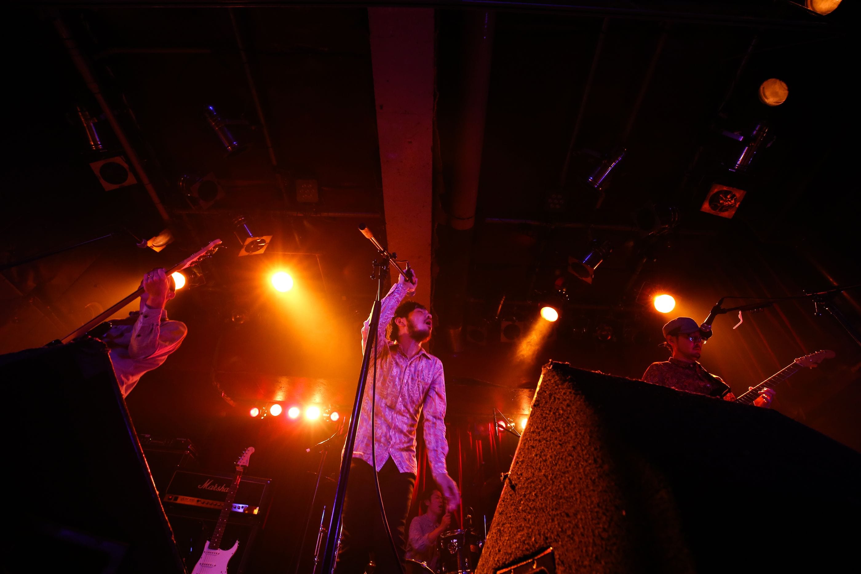 Potomelli on stage with the band, lit by warm amber spotlights.